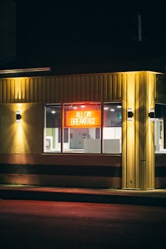 Cozy corner restaurant illuminated by neon lights offering all day breakfast at night.