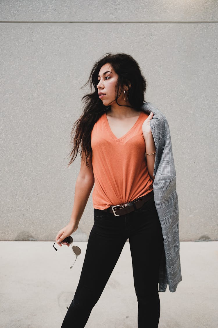 Woman In Orange Shirt Carrying A Blazer On Her Shoulder 