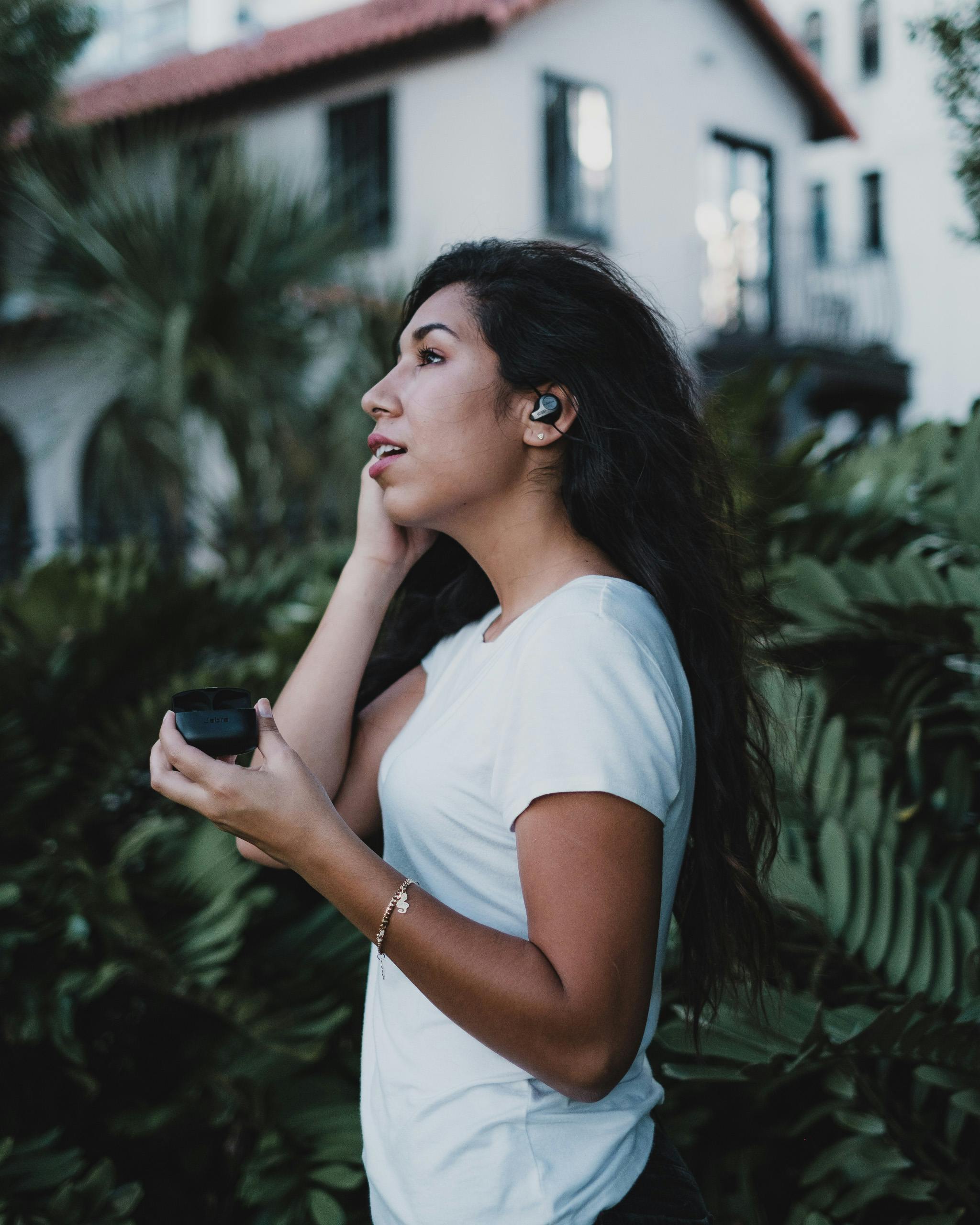 a woman in a white shirt using wireless earbuds