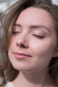 Close-up of a relaxed woman with eyes closed and subtle smile.
