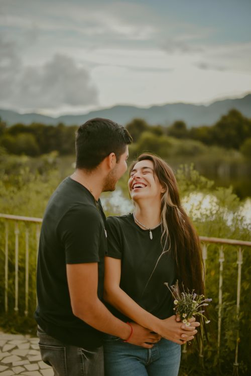 Free Happy couple laughing and holding flowers in San Cristóbal de las Casas, Mexico. Romantic outdoor setting. Stock Photo