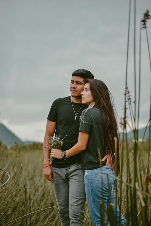 Free A Man and a Woman Standing Together in a Grass Field Stock Photo