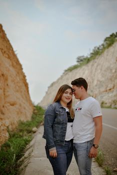 A young couple shares a moment of affection on a scenic road lined by cliffs in Mexico.