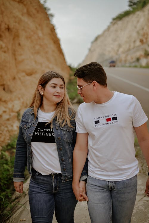 A Man and a Woman Holding Hands While Walking Near the Road