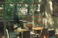透过大玻璃窗，阳光洒在室内咖啡馆宁静的环境中，映照着时尚的桌椅