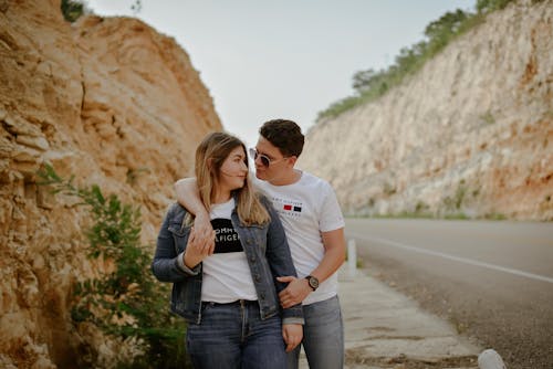 Man in White Crew Neck T-shirt Kissing Woman in Blue Denim Jeans