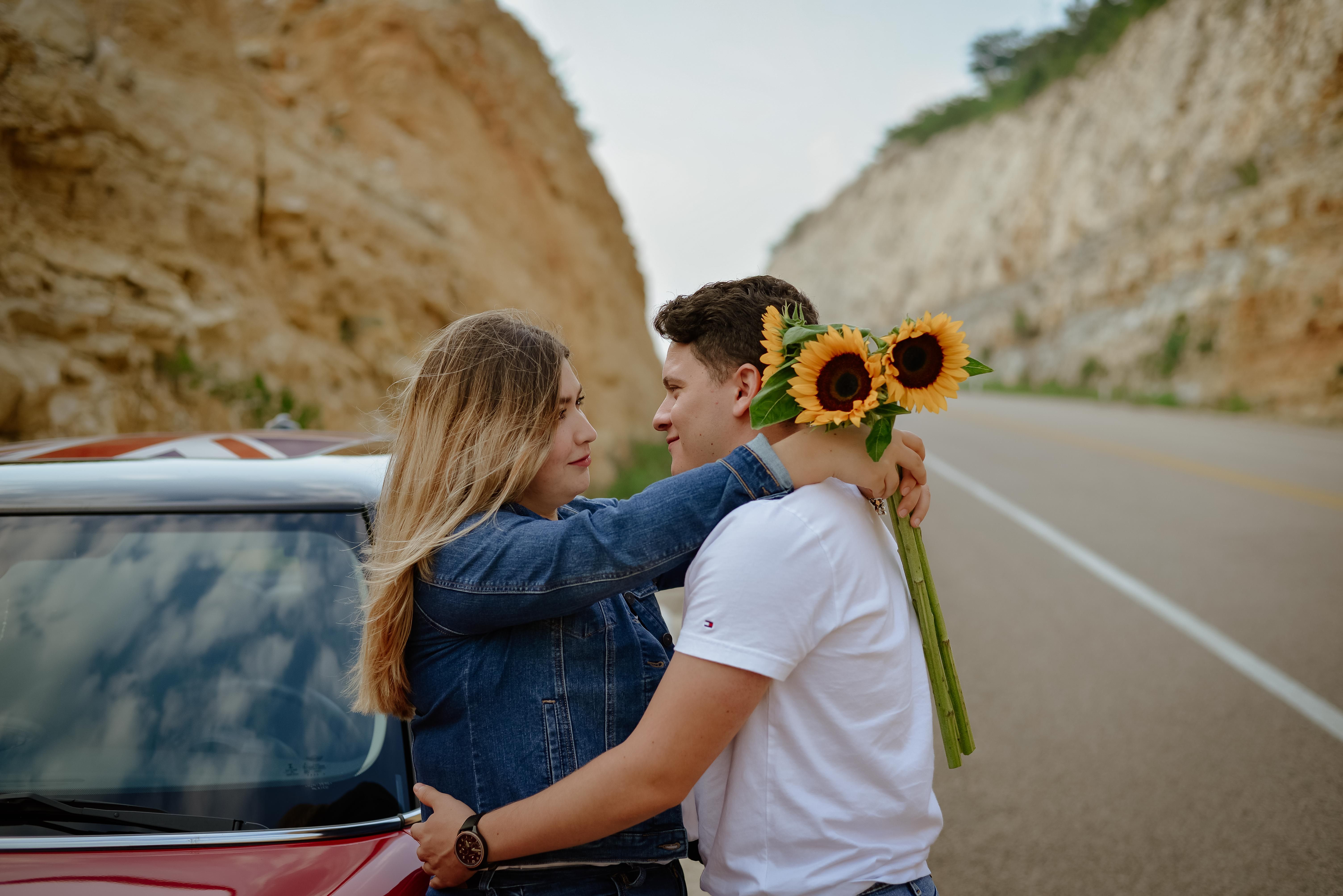 Foto de stock gratuita sobre abrazando, afecto, amor, apoyado, carretera, cercanía, coche, flor amarilla, girasol, hombre, mirando el uno al otro, mujer, pareja, relación, romance