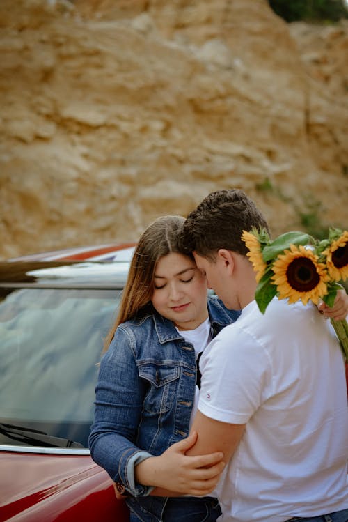 Man in White Shirt Hugging Woman in Denim Jacket