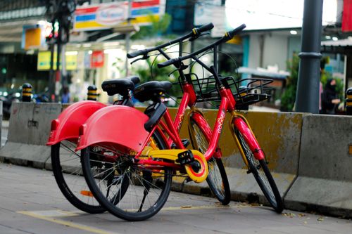 Free Bright red bicycles parked on a city street in Jakarta, Indonesia, highlighting urban transportation. Stock Photo