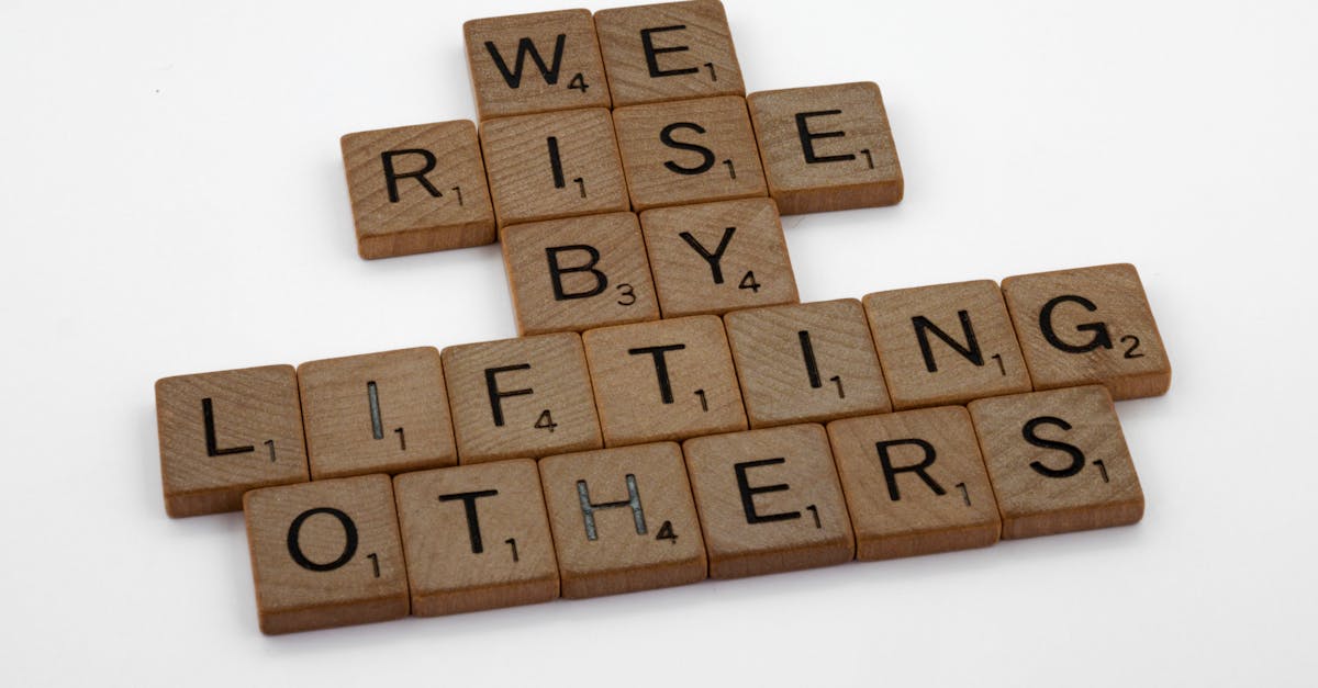 Scrabble tiles forming the quote 'We rise by lifting others' on a white background.