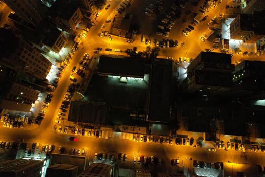 Aerial drone shot of a cityscape in Kuwait at night, highlighting illuminated streets and buildings.