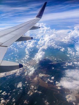 Stunning aerial view from an airplane window showing clouds and landscape below in Bijayanagar, India.