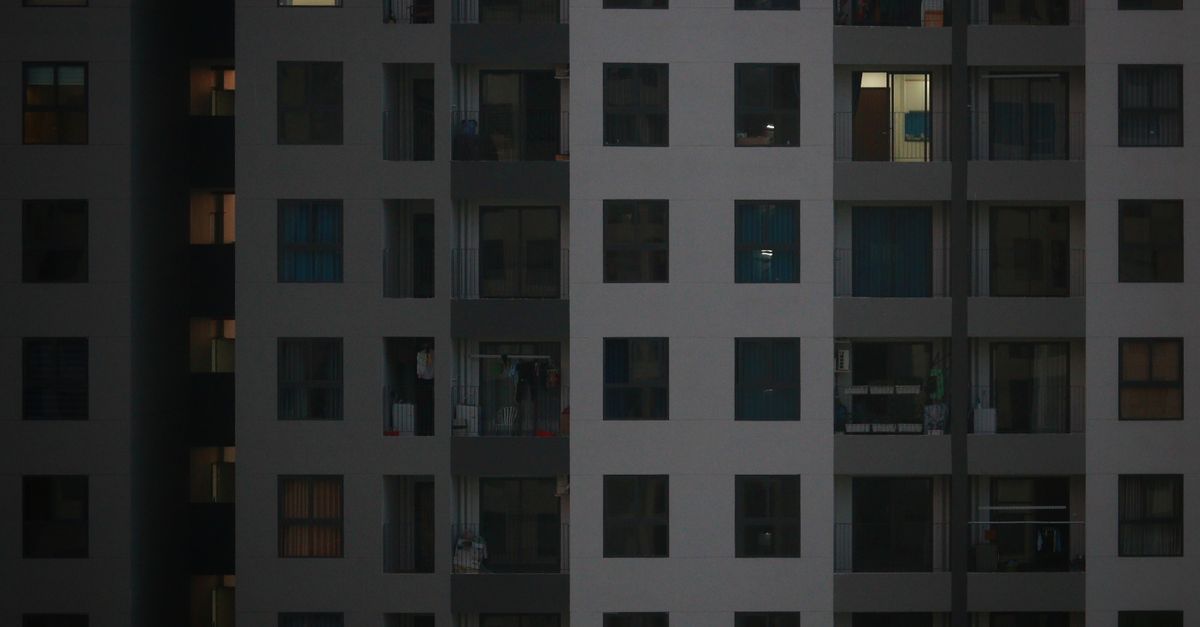 A detailed view of a modern apartment building facade with illuminated windows at night.