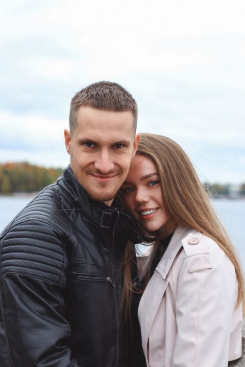 Free A young couple in jackets embracing by a lake, showcasing love and togetherness outdoors. Stock Photo