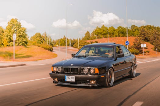 Classic black BMW E34 cruising smoothly on a clear day with lush greenery in the background.