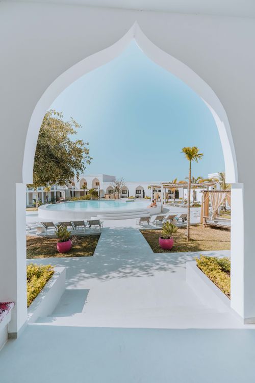 Free A luxurious Mediterranean-style resort showcasing a pool view through an arched entryway, evoking relaxation. Stock Photo