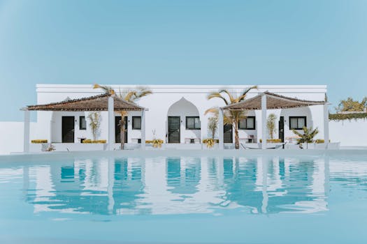 Elegant white villa in Zanzibar featuring a stunning swimming pool and palm trees under a blue sky.
