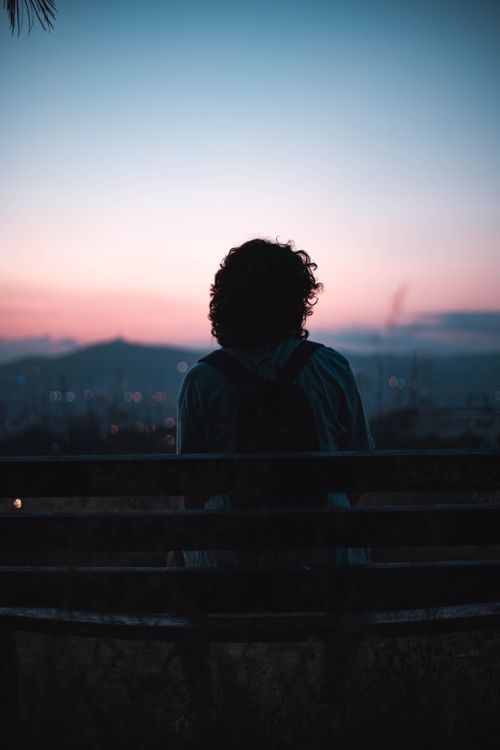 Free Silhouette of a person sitting on a bench during sunset in Barcelona, Spain, with a beautiful skyline view. Stock Photo
