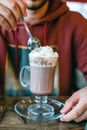 Person Holding Stainless Steel Spoon and Clear Glass Mug With Brown Liquid