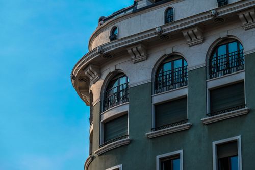 Free A green modern building with ornate arched windows and balconies against a clear blue sky. Stock Photo