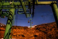 在晴朗的蓝天下，绿色钢缆车穿越岩石山脉