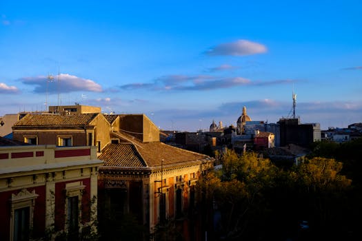 意大利城市屋顶、树木和教堂圆顶在蓝天下呈现迷人的日落景观