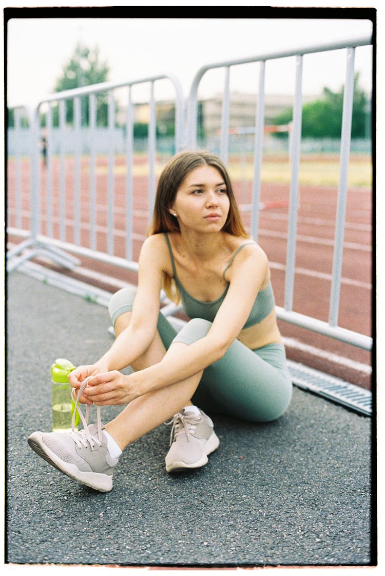 Young Woman Tying Shoes On Athletics Track