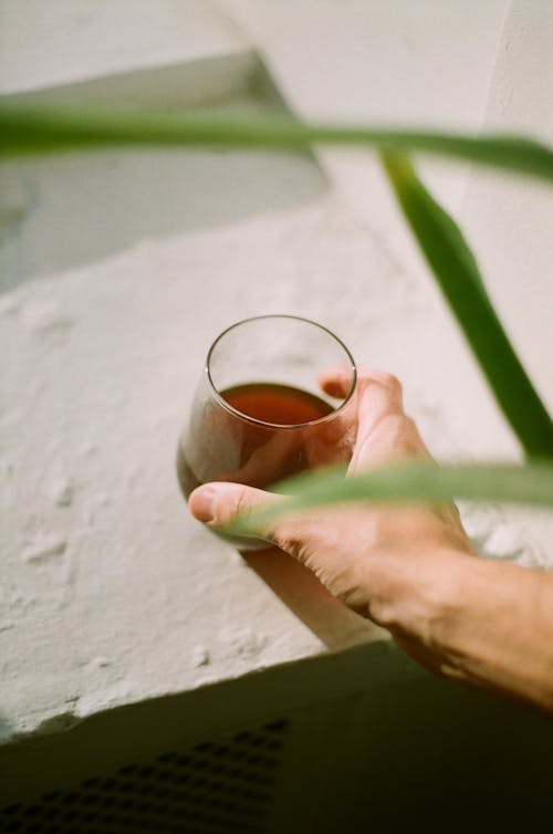 Free Close up on hand holding glass of tea on wall Stock Photo
