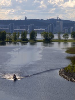 在风景如画的城市湖泊上，一名骑手正驾驶着水上摩托车，背景是城市的天际线，场面十分激动人心