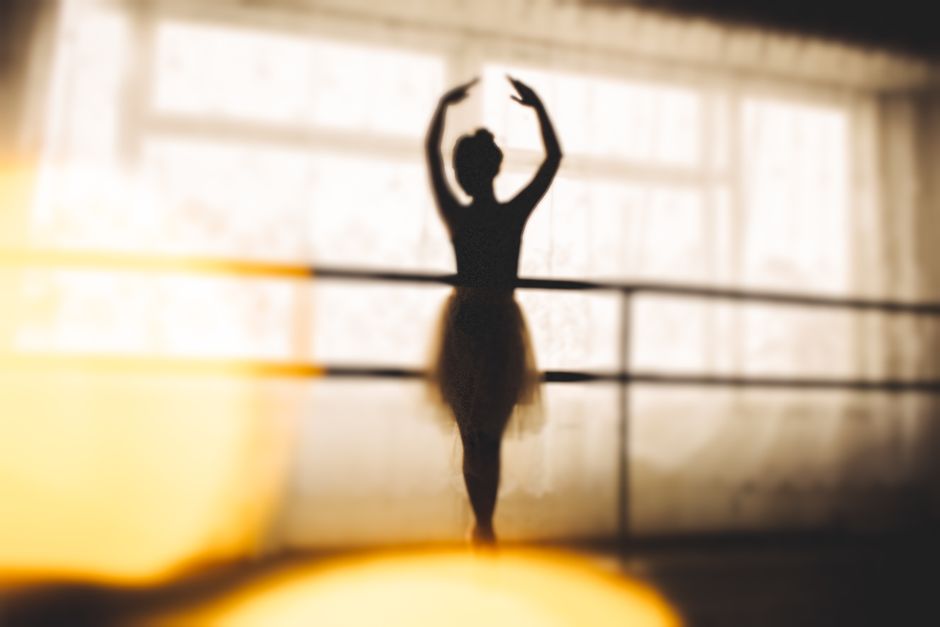 Elegant silhouette of a ballerina posing gracefully in a sunlit dance studio.