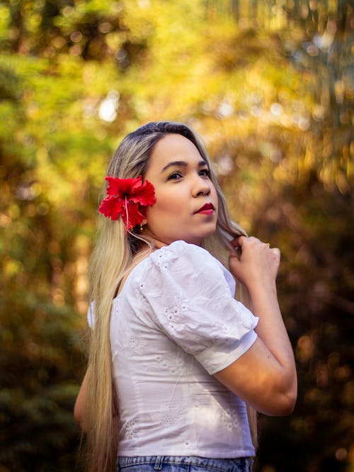 Woman in White Blouse with a Red Flower on Her Ear