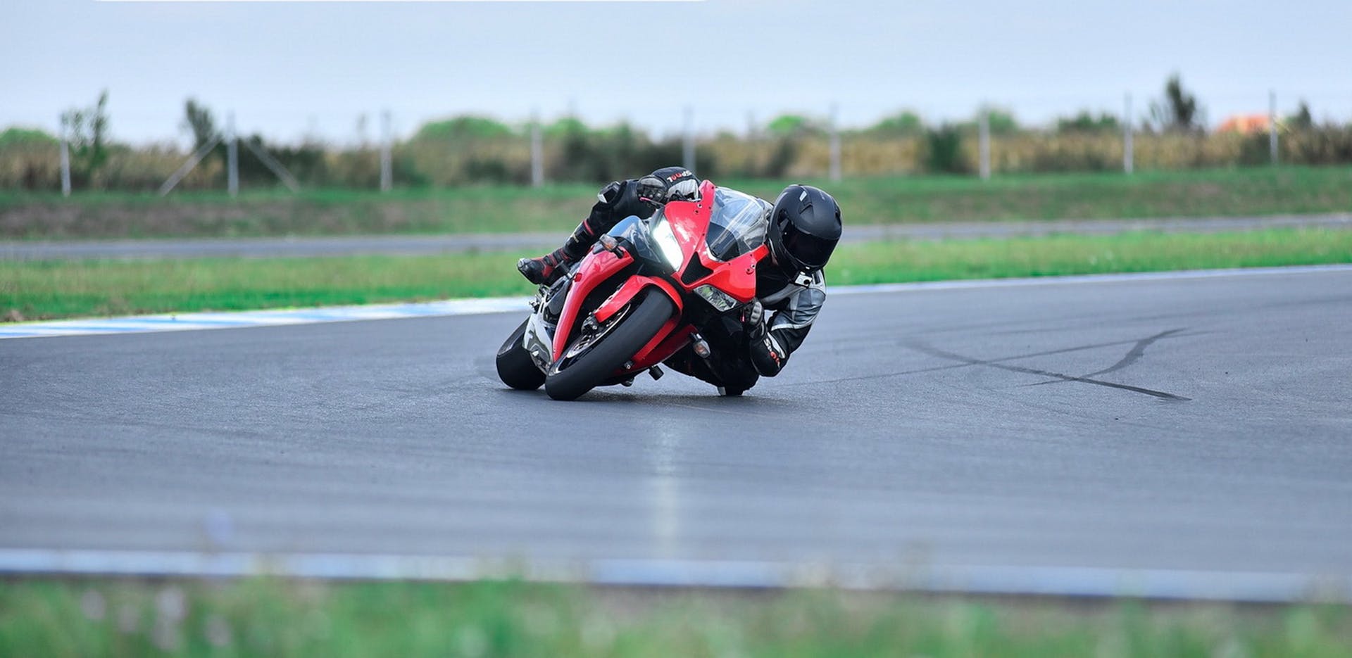 Motorcyclist wearing a helmet leans into a turn on a race track.