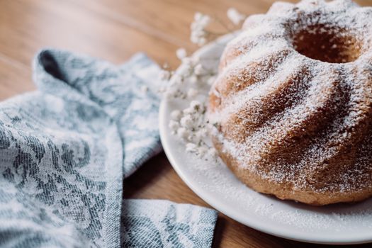 A beautifully baked bundt cake dusted with powdered sugar sits on a plate, perfect for dessert lovers.