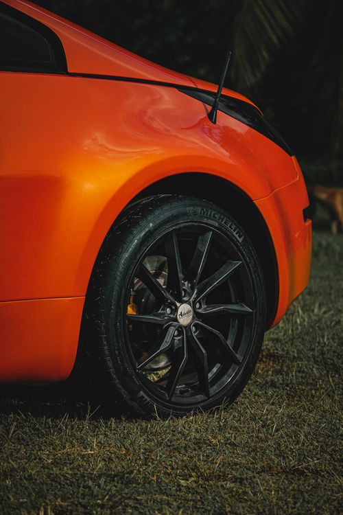 Free Dynamic close-up shot of an orange sports car wheel showcasing sleek design and vibrant color. Stock Photo