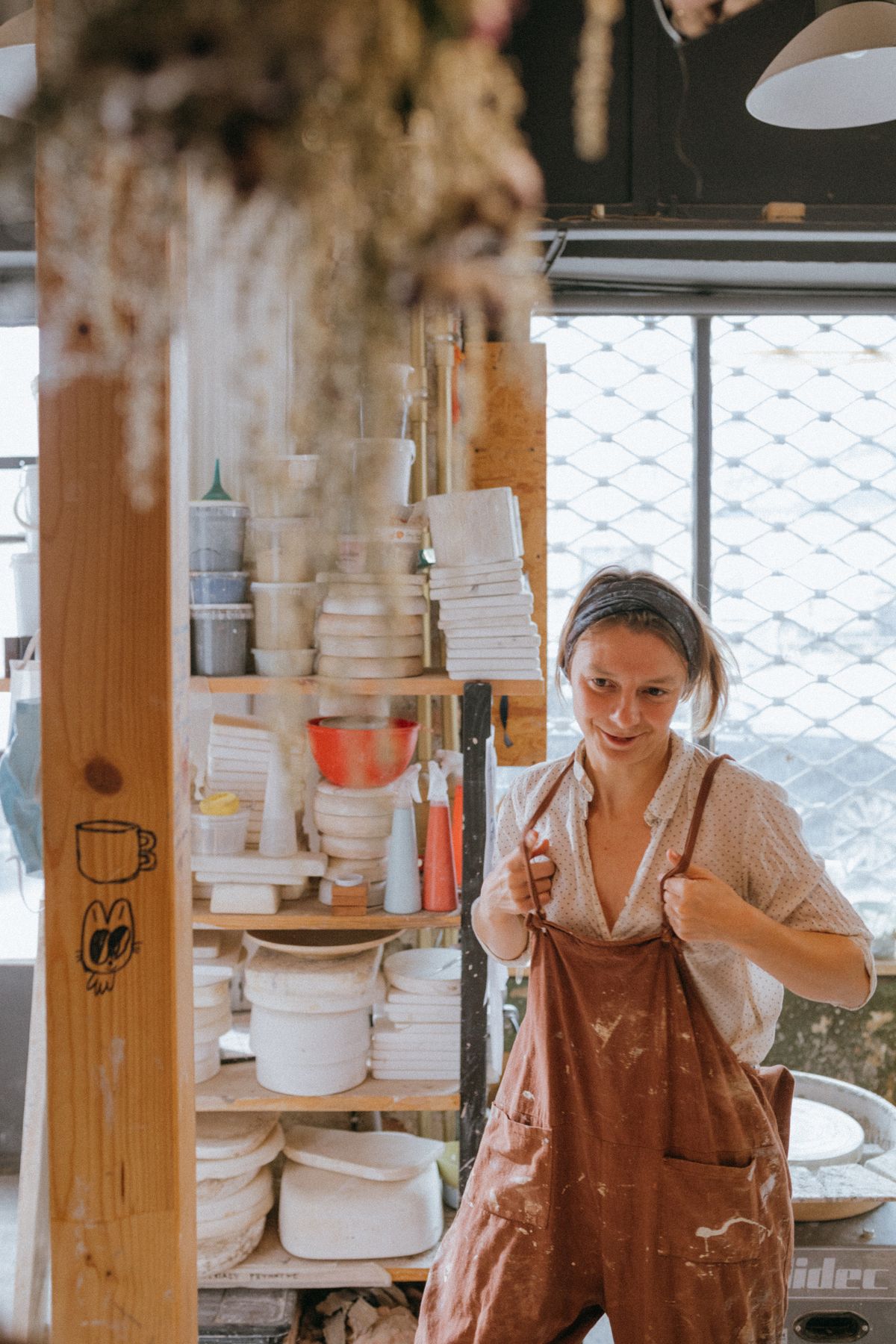 A smiling maker in an apron among studio shelves
