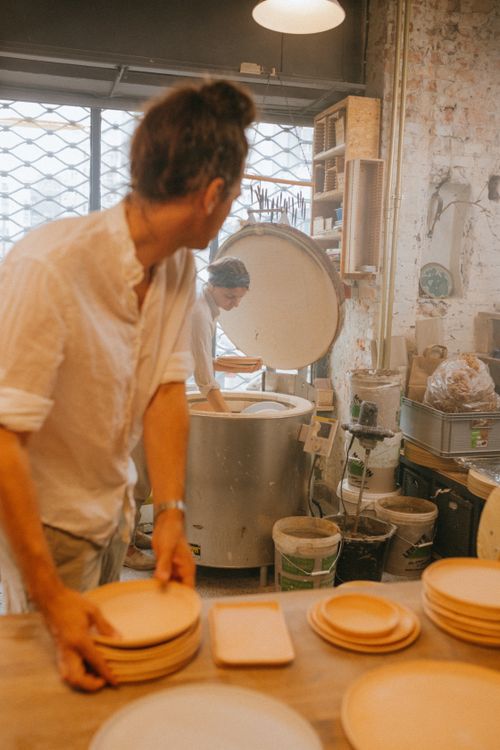 Free Two artisans skillfully crafting ceramic plates in a workshop, showcasing traditional pottery techniques. Stock Photo