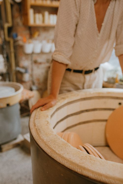 Free A potter working in a rustic ceramics workshop with handmade pottery pieces in a kiln. Stock Photo