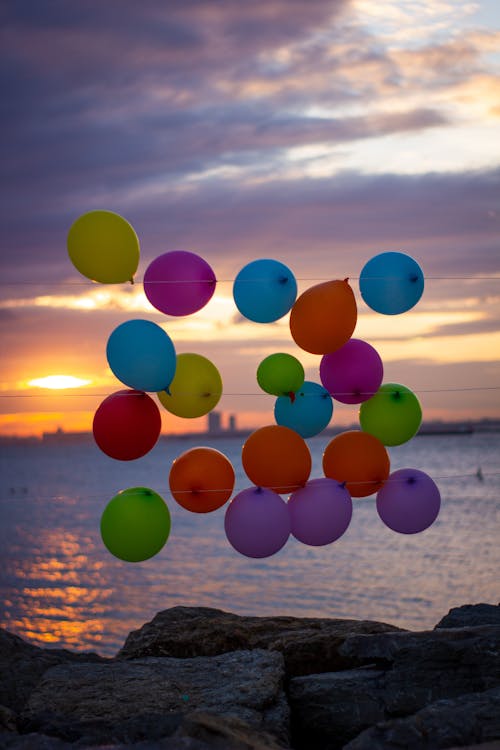 Free Colorful Balloons on Strings Near Rocky Coast Stock Photo