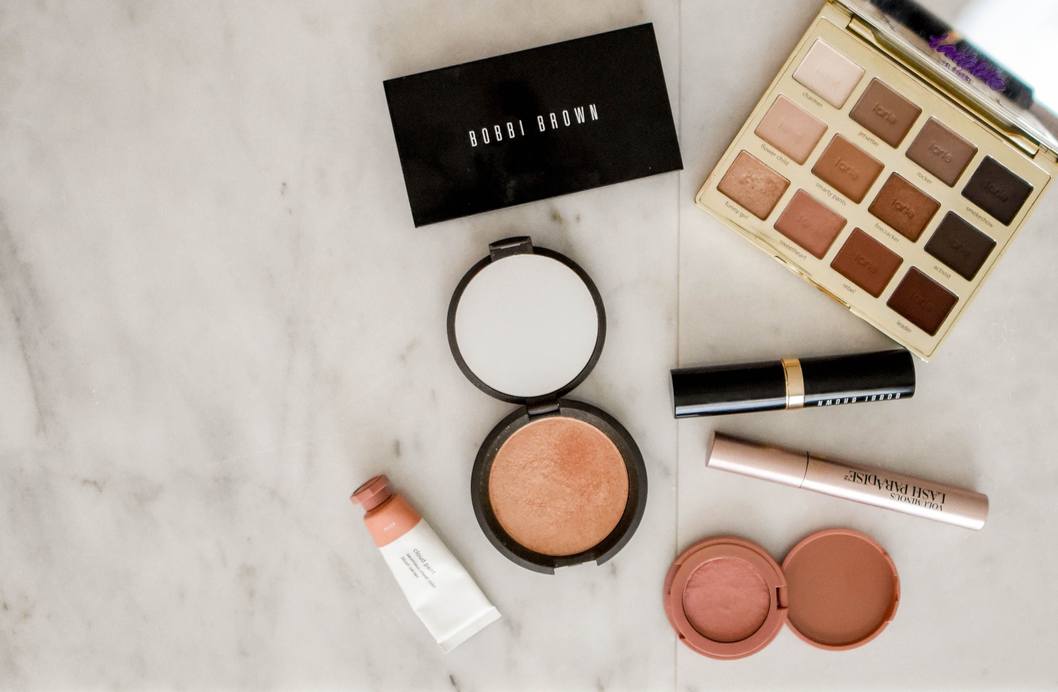 Makeup products neatly grouped on a marble surface, an organized vanity system