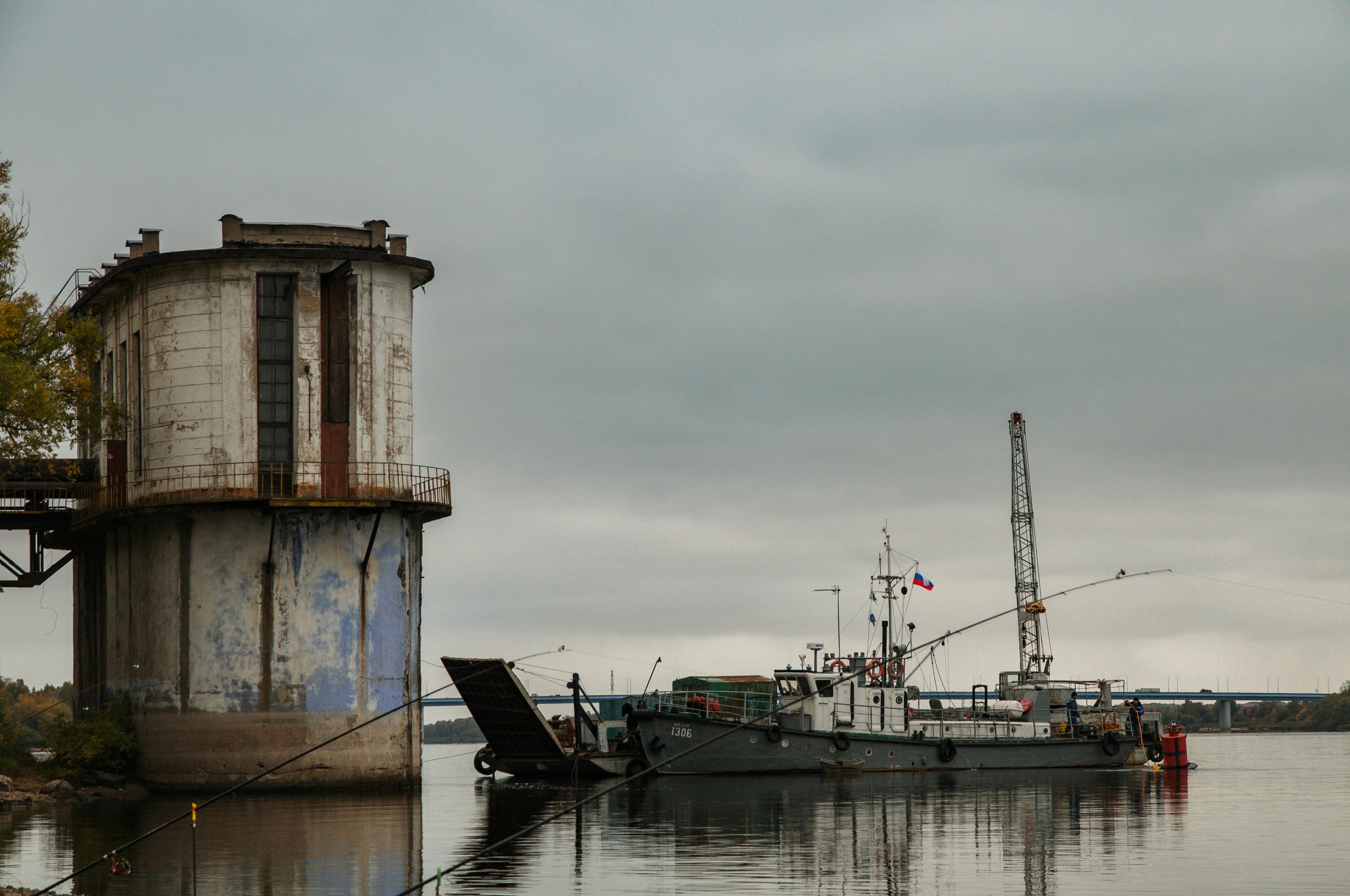 Industrial vessel docked by an old structure in a harbor with a gloomy sky.