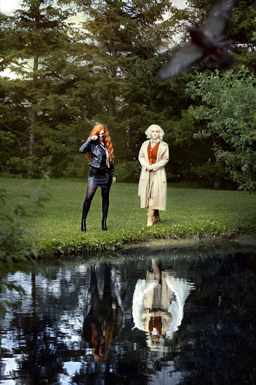 Women Standing on Green Grass Near the Lake