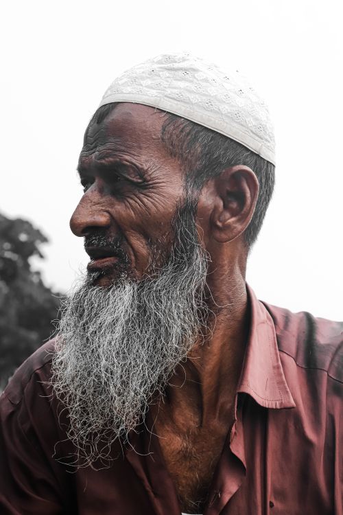 Free Close-up portrait of a senior man with a gray beard wearing a cap, captured outdoors. Stock Photo