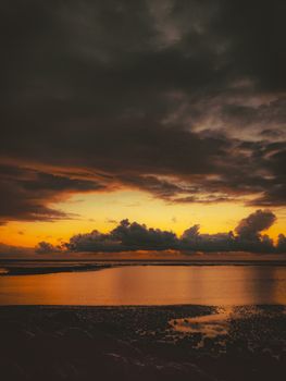 Capture of a stunning coastline at sunset with dramatic clouds and golden reflections on the water.