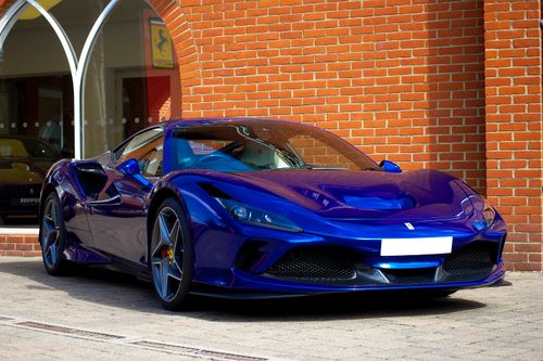 Free A stunning blue Ferrari sports car parked outdoors against a brick wall in the UK. Stock Photo