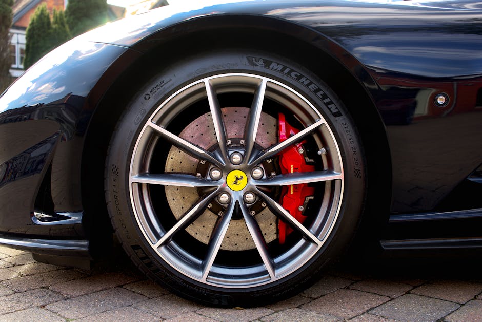 Detailed image of a Ferrari sports car wheel with red brake caliper, shot outdoors.