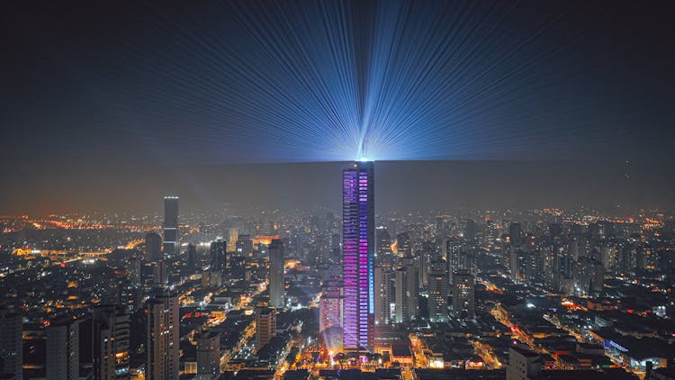 Illuminated Skyscraper Projecting Light In Night Sky