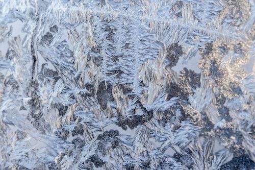 Free Close-up of frosty ice crystals forming intricate patterns on a window during winter. Stock Photo