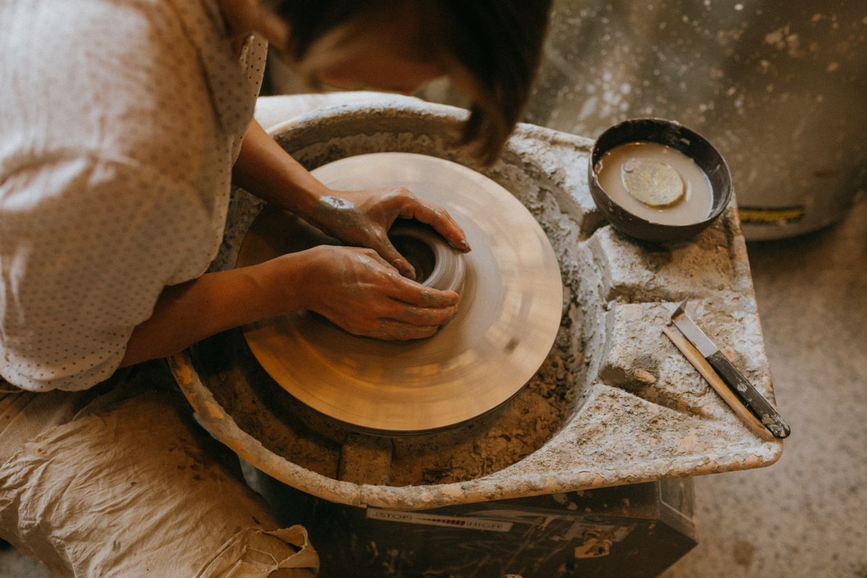 Hands steadying a large thrown bowl on the wheel