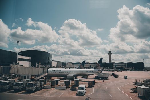 A United airplane parked on the airport apron under a scenic cloudy sky.