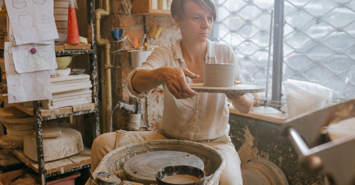 Une artisan concentré en train de façonner de la poterie sur un tour dans un atelier de céramique.